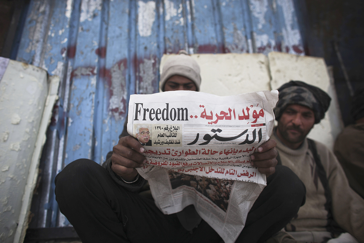 An anti-government protester reads a newspaper near Tahrir Square in Cairo, Egypt, Monday, Feb. 7, 2011. The protests, which saw tens of thousands of people massing daily in downtown Cairo for demonstrations that at times turned violent, have raised questions about the impact on the economy. More than 160,000 foreign tourists fled the country in a matter of days last week, in an exodus sure to hammer the vital tourism sector. The arabic on the newspaper headline reads "The birth of freedom".(AP Photo/Tara Todras-Whitehill)