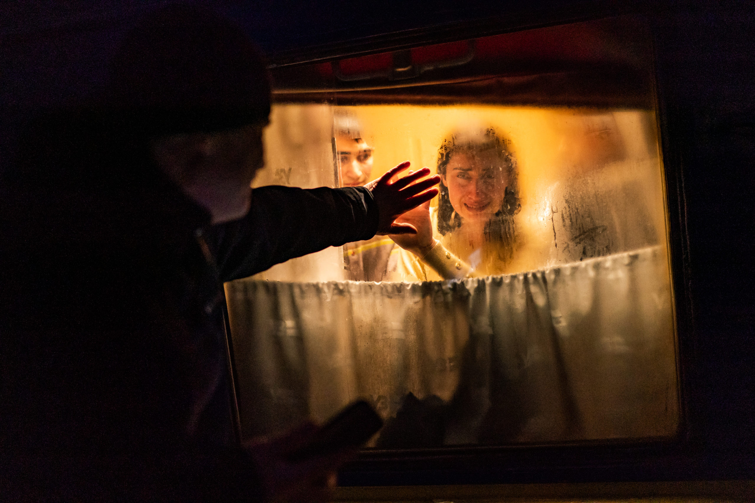 George Keburia puts his hand on the glass window of a train. On the other side of the window, his wife Maya puts her hand on the window where George put his.