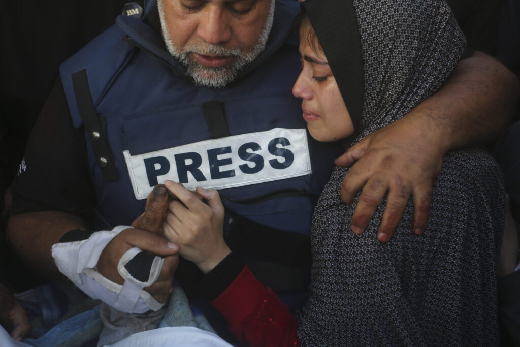 close up photograph of a journalist embracing family member during a funeral