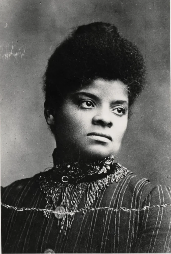 black and white picture of a young Ida. B Wells in the 1890s. she is wearing a high-neck blouse/dress.