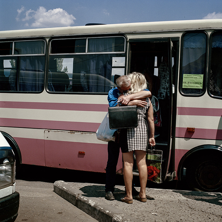 two people embrace outside of a bus stop