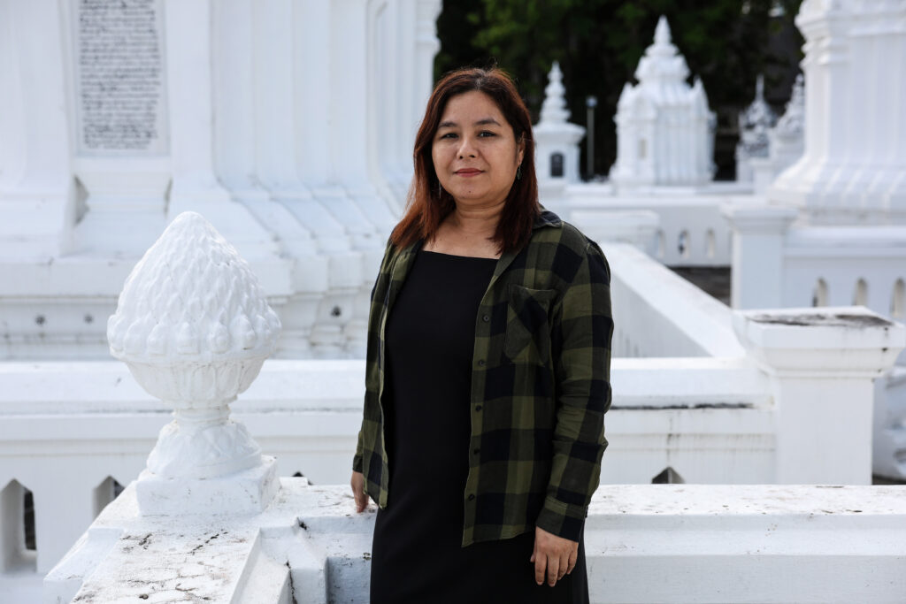 woman standing outside a temple, the sculptures, stairs, and walls are all painted white