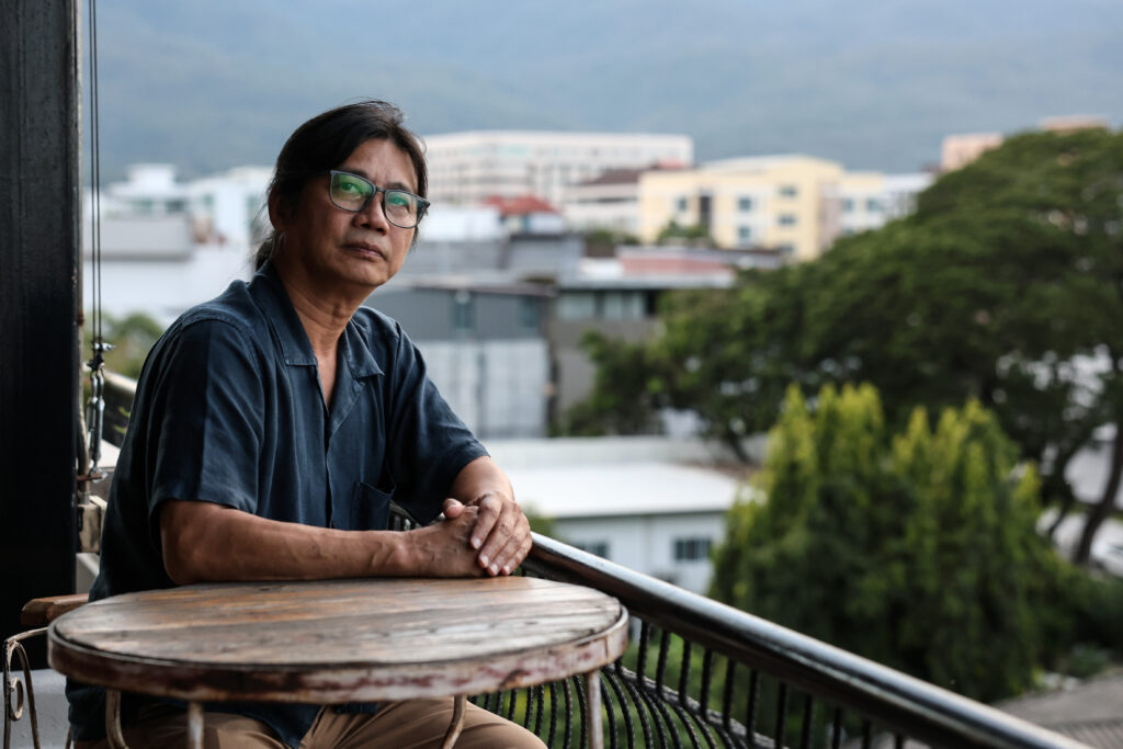 man sits at a corner table on a rooftop bar balcony
