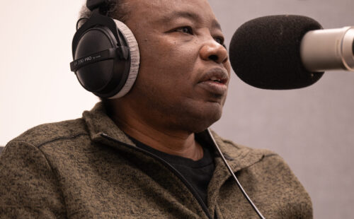 a man sits at a microphone in a professional podcasting studio