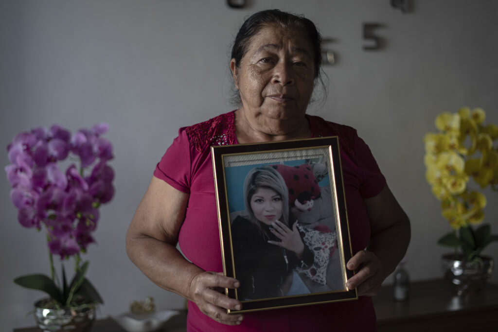 a woman holding up a picture of her daughter in a gold picture frame