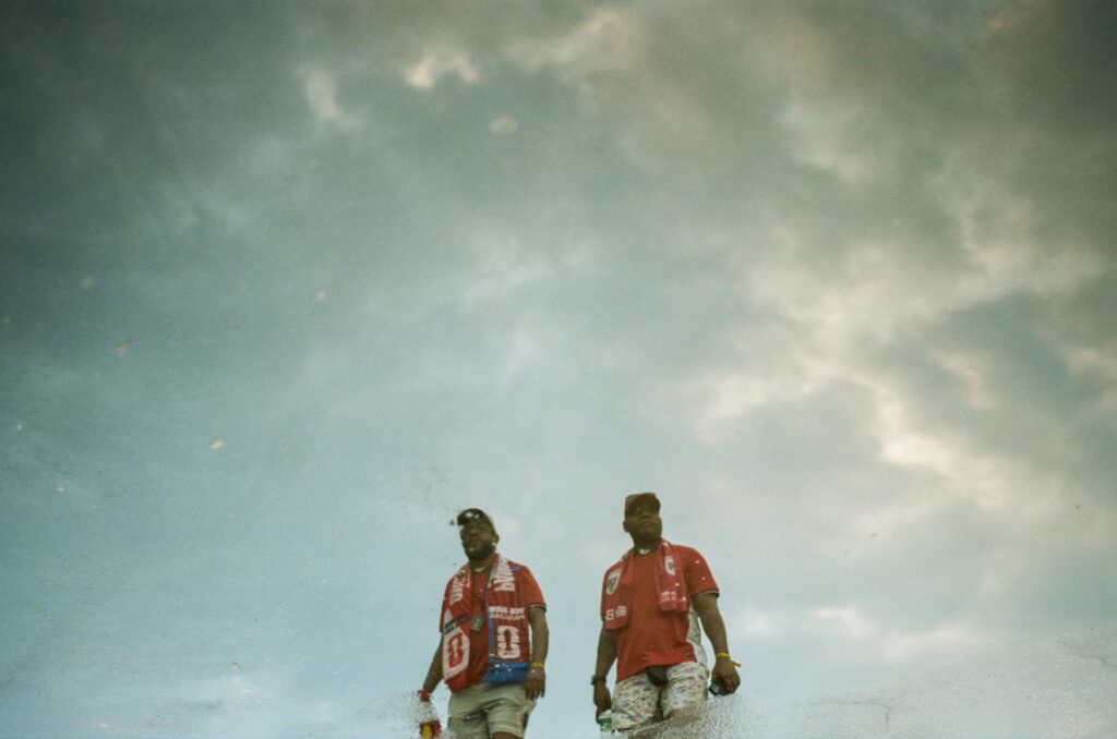 two panamanian fans walk against a cloudy sky