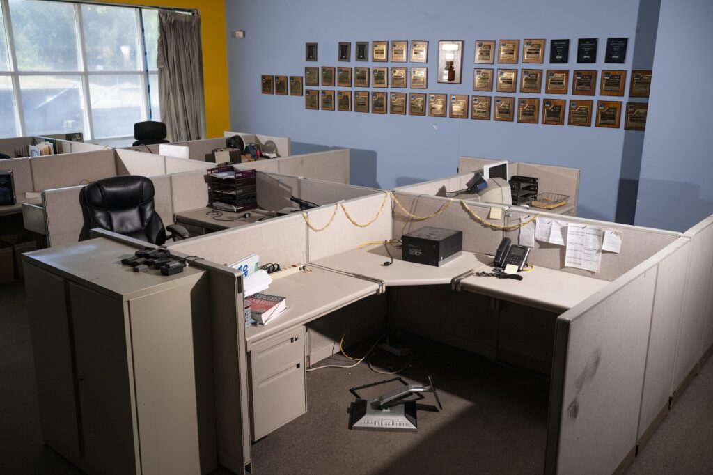 empty desks in a newsroom with baby blue walls and 90s office cubicle furniture