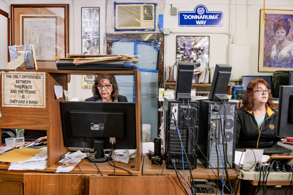 two women hard at work at their desks,covered in computer wires and papers