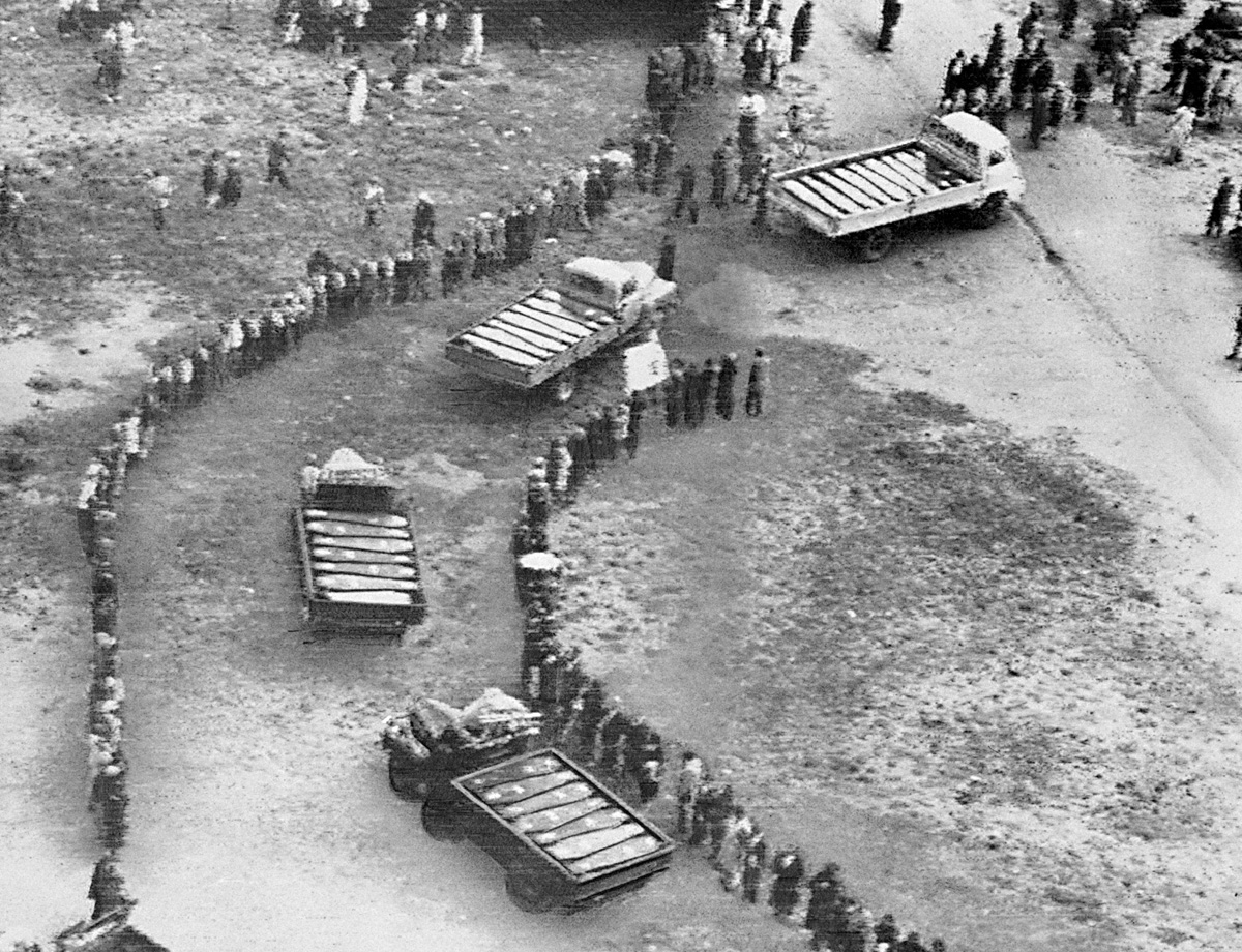 Trucks carrying coffins roll by mourners at a mass funeral in 1960 following the Sharpeville massacre