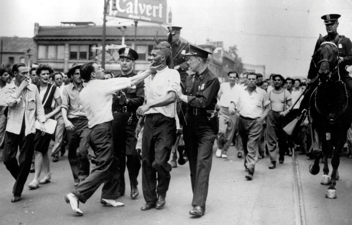 A black man, shot in the stomach during riots in Detroit, Michigan in 1943, is assaulted