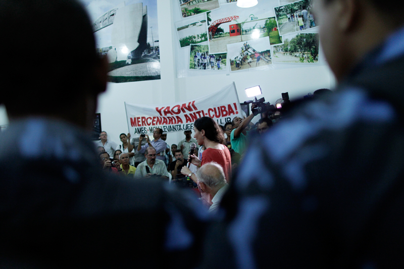Yoani Sánchez, center, labeled on a banner as an anti-Cuba mercenary, speaks in Brazil in 2013