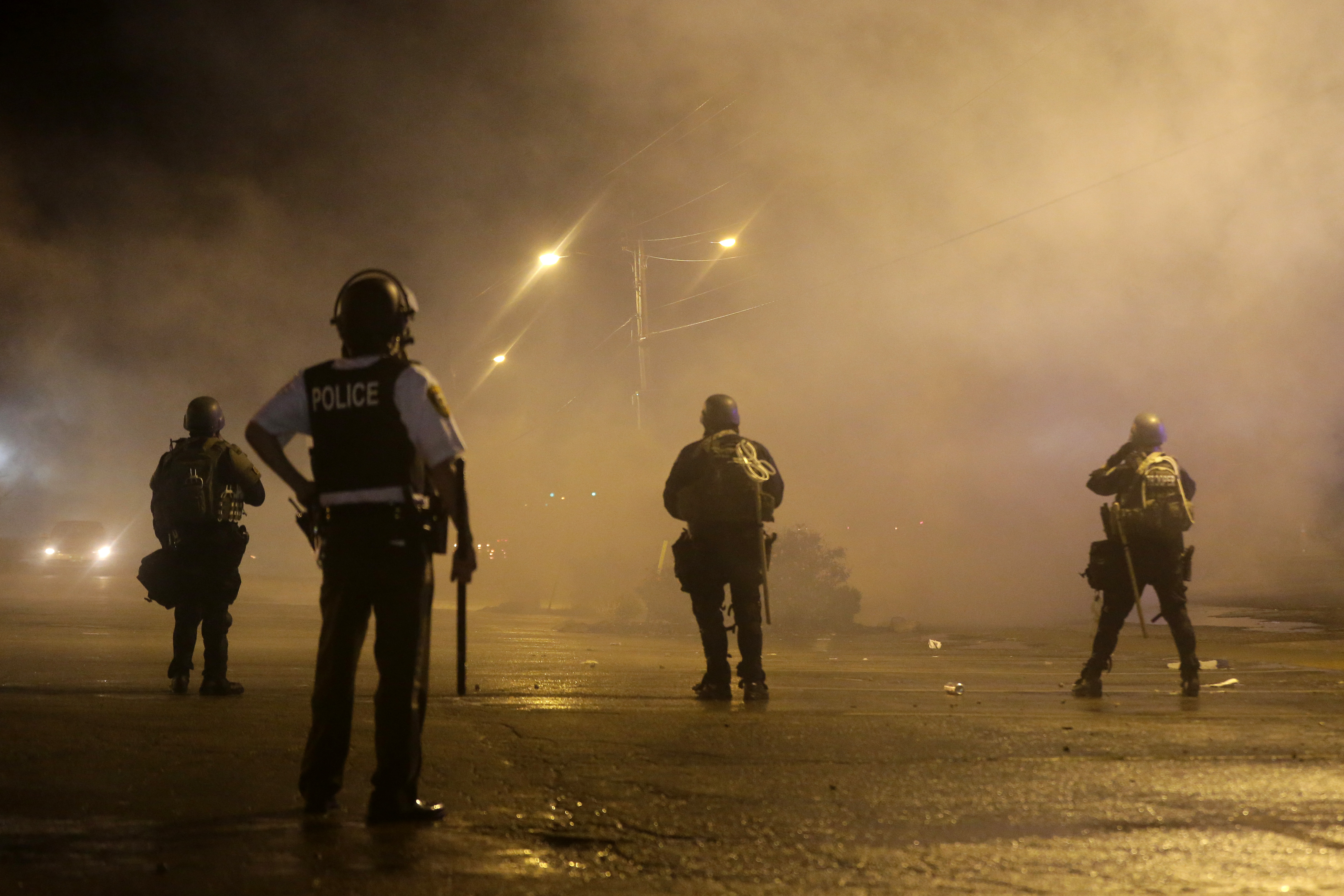 Police officers watch as tear gas is used to dispel a crowd in Ferguson, Missouri, in August
