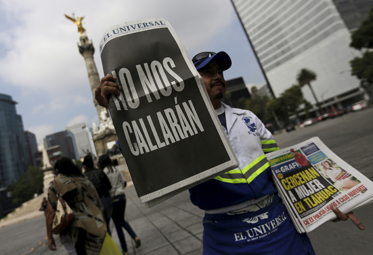 A street vendor sells copies of Mexico's leading daily El Universal newspaper with a blackened-out front page that reads "We will not be silenced"