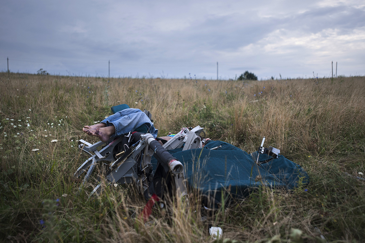 FOR STORY UKRAINE MH17 WHERE THINGS STAND - FILE - Saturday, July 19, 2014 file photo a body sitting in a plane chair at the crash site of a Malaysia Airlines jet near the village of Hrabove, eastern Ukraine. A year since a Malaysia Airlines Boeing 777 was blown out of the sky over war-ravaged eastern Ukraine, killing 298 people, there has been little definitive progress in determining what brought down Flight MH17. (AP Photo/Evgeniy Maloletka, file)