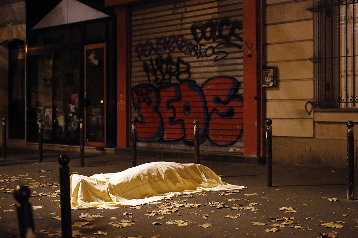 FILE - In this Friday, Nov. 13, 2015, file photo, a victim of an attack in Paris lays dead outside the Bataclan theater, Paris, Friday Nov. 13, 2015. Coming soon after the Islamic State group claimed the downing of the Russian plane in Egypt and deadly suicide bombings in Lebanon and Turkey, the Paris attacks appear to signal a fundamental shift in strategy toward a more global approach that experts suggest is likely to intensify