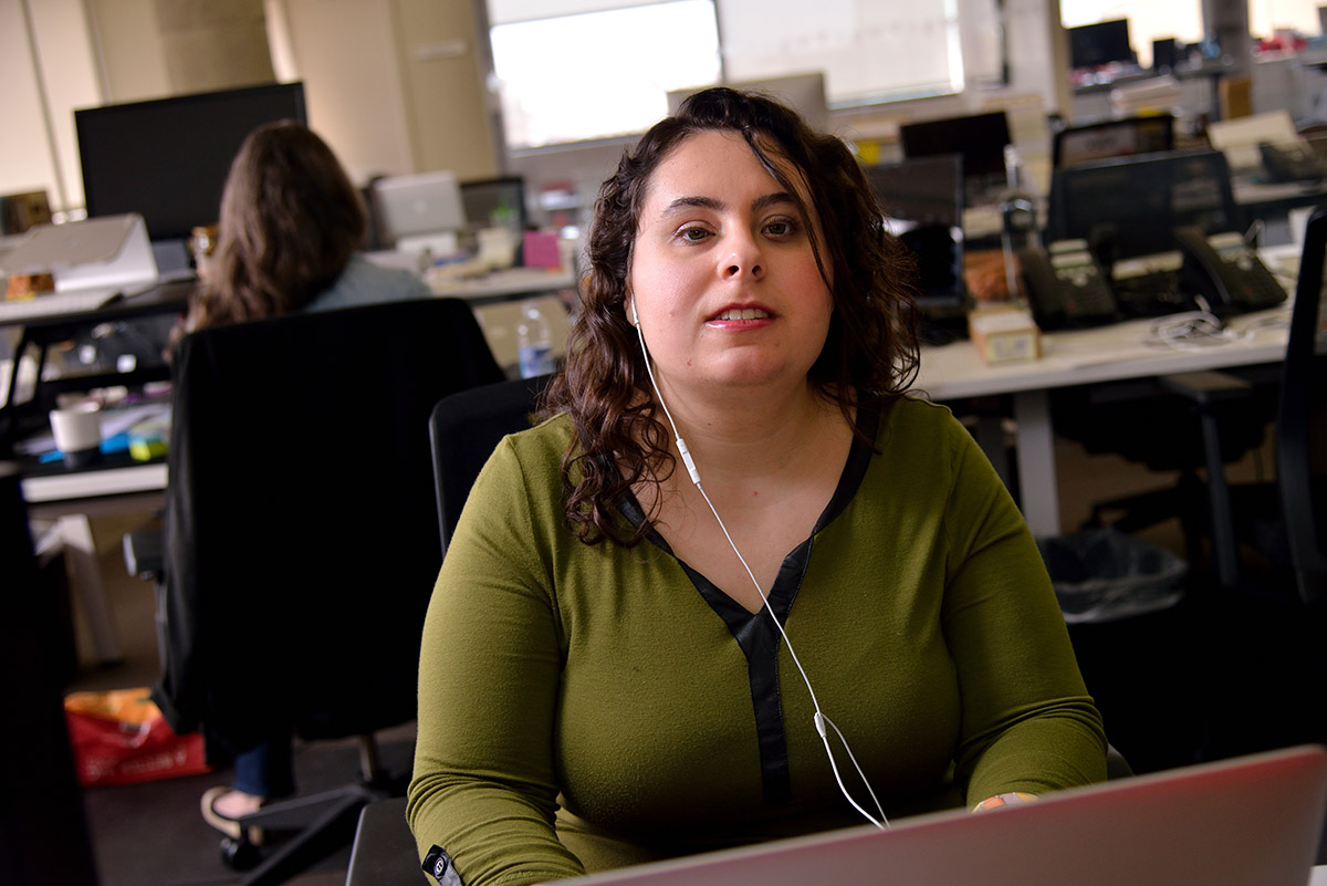 Michelle Hackman, political reporter for Vox, works in the newsroom with a single earphone in her ear