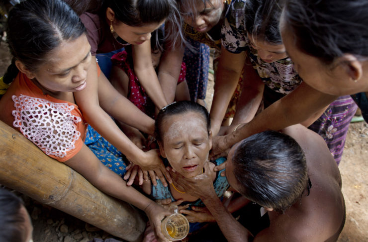 Women attend to  
Khin Than, who fainted during a reunion with her son, one of hundreds of enslaved fishermen who returned to Myanmar following the AP's Pulitzer-winning "Seafood from Slaves" investigation.