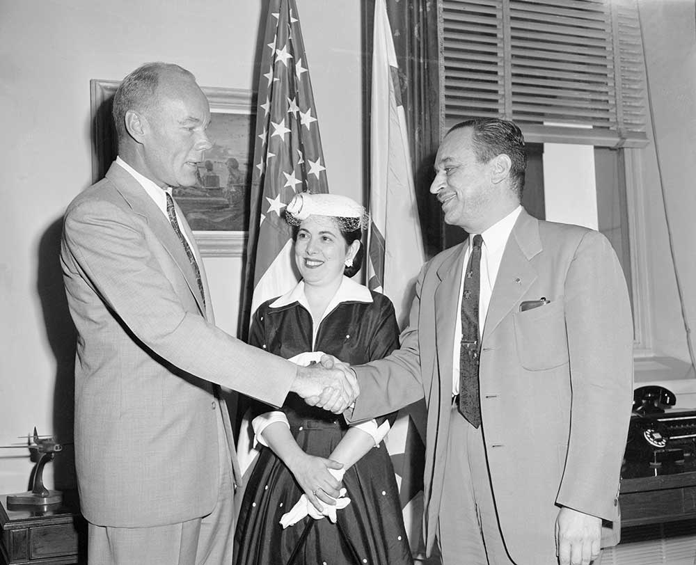 A government official welcomes back to duty Navy employee Abraham Chasanow, his wife at his side