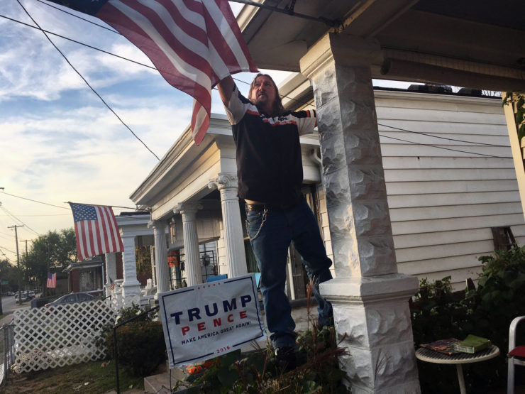 Terry Wright, a 59-year-old retired union painter, adjusts the U.S. flag on his porch in Portland, a white, working class neighborhood in Louisville, Ky. 