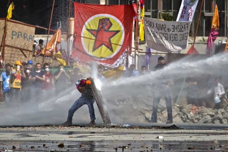 A protester takes cover from a Turkish riot police water canon during clashes in Taksim Square in Istanbul in June 2013.  Though TV stations declined to cover the Gezi Park protests, the news spread on social media
