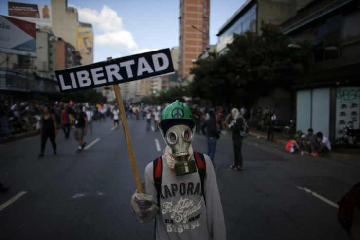 A masked protester holds a sign that reads "Liberty" in Spanish  during clashes with government security forces in Caracas in May. Censorship in Venezuela has increased as the political turmoil continues to escalate