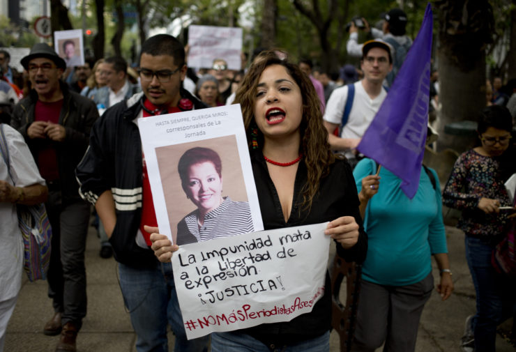 A woman holding a photo of murdered Mexican journalist Miroslava Breach and a sign that reads, "the impunity kills freedom of speech, justice," during a demonstration in Mexico City in March