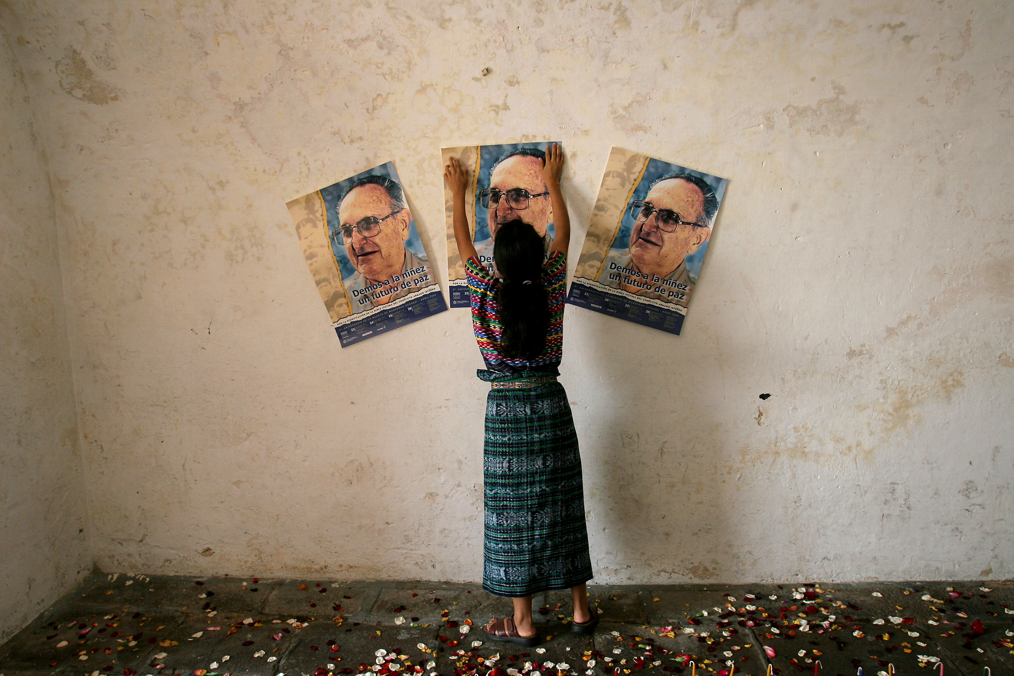 An indigenous woman places a poster of Bishop Juan Gerardi Conedera at a Catholic church in Guatemala City in April 2006 to mark the anniversary of his murder