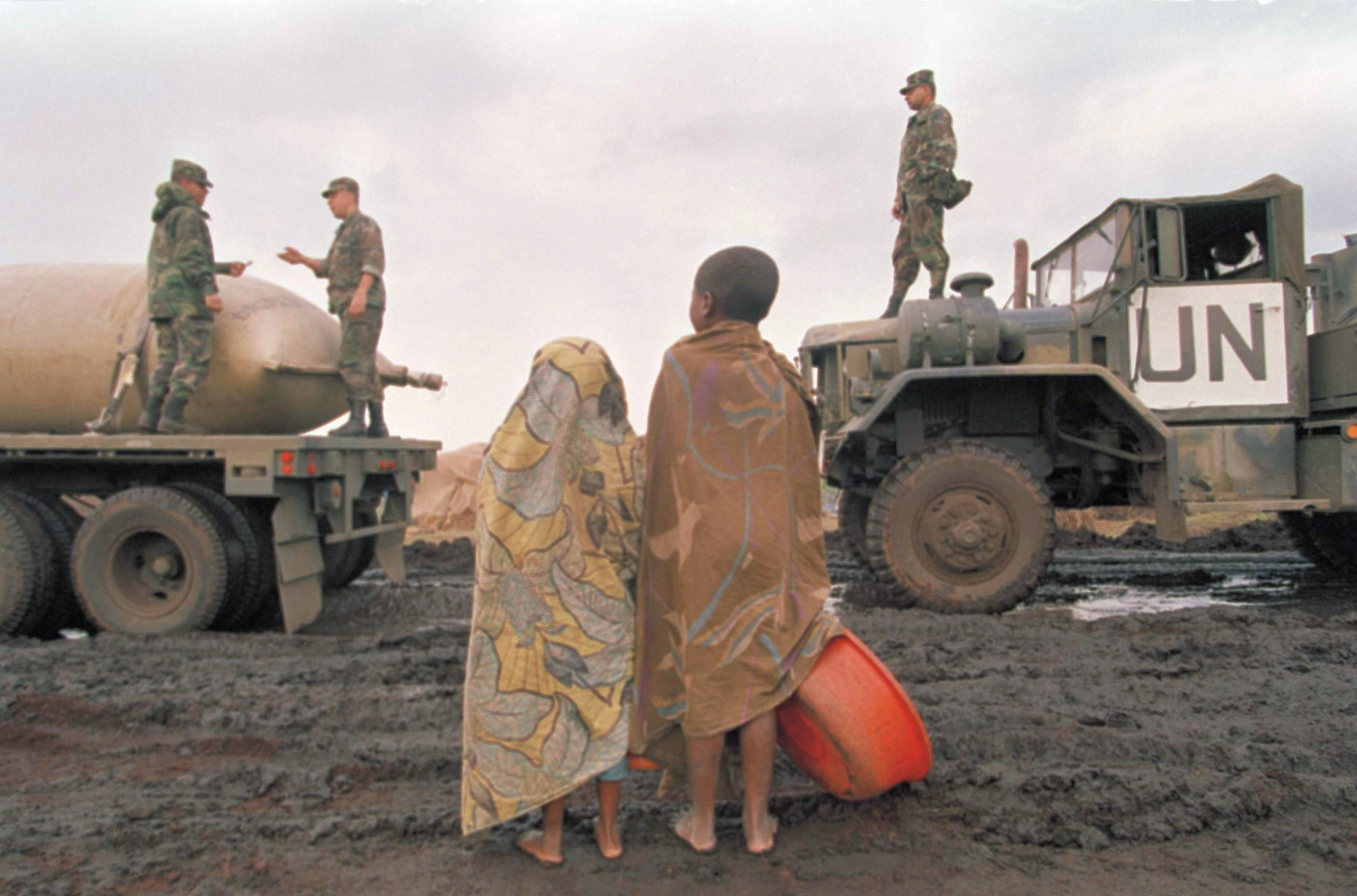 Young Rwandans watch as U.S. Army Rangers unload fresh water from trucks in the Kibumba refugee camp near Goma in August 1994