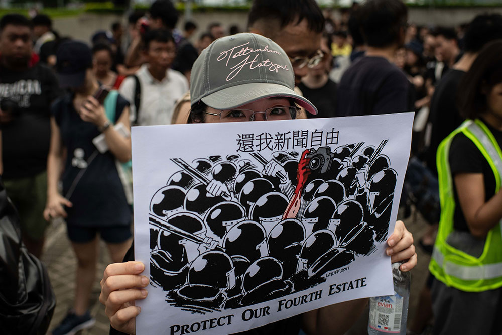 A protester holds a placard during a July march, called  "Stop Police Violence, Defend Press Freedom,” held by media groups and journalist trade unions in Hong Kong to express demands that police facilitate the work of news media and respect press freedom