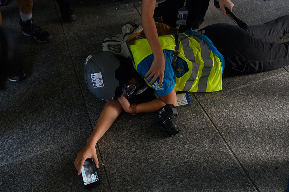 A reporter lays down after getting hit during clashes following an unsanctioned protest march through Hong Kong on September 29, 2019