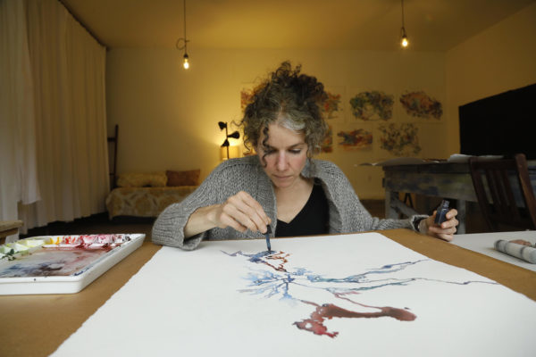 Oregon artist Daniela Molnar works on a painting about climate change