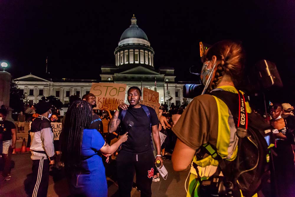 A protester is interviewed in front of the state capitol in Little Rock