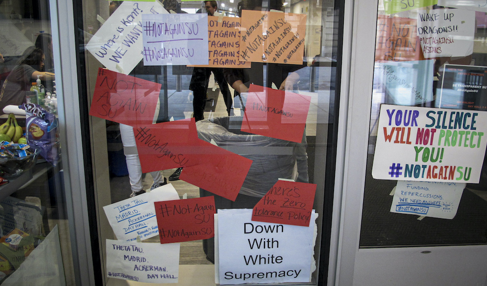 Signs posted on windows and doors at Syracuse University in the fall of 2019 display anti-racism expressions following reports of racist graffiti and other incidents at the school