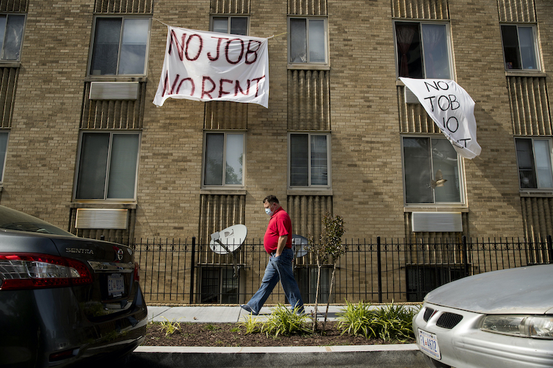 Signs read “No Job No Rent” hang from the windows of an apartment building in Northwest Washington