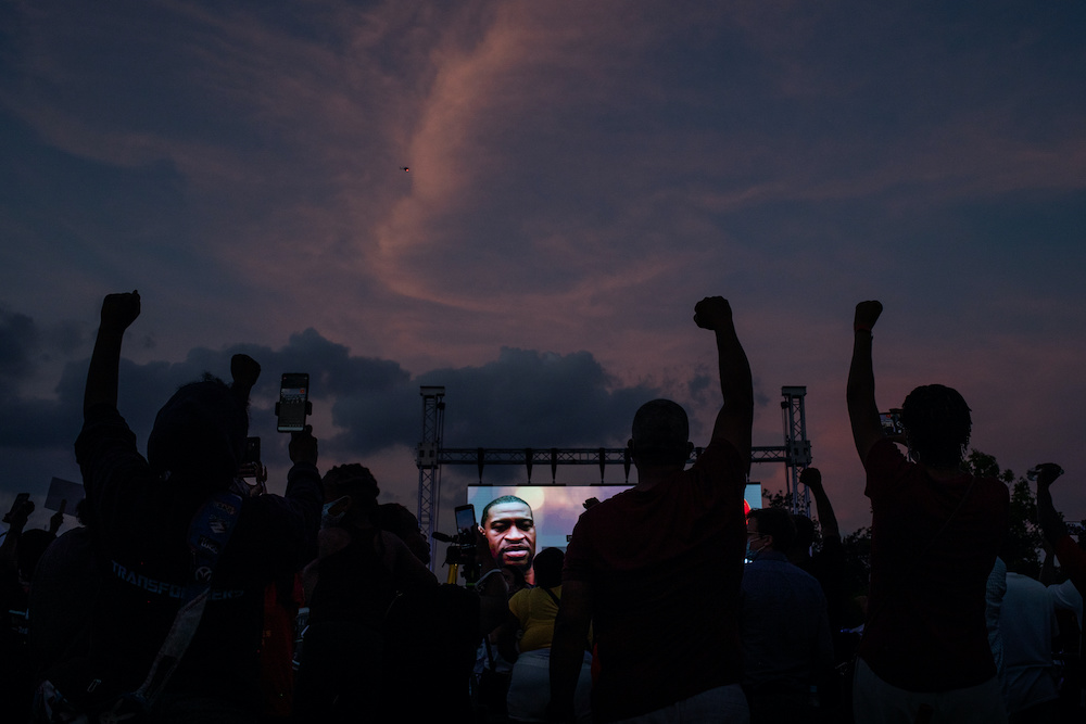 During a June vigil honoring George Floyd, held on the Yates High School field where Floyd played football in Houston, Texas, local residents and alumni raise their hands in solidarity 