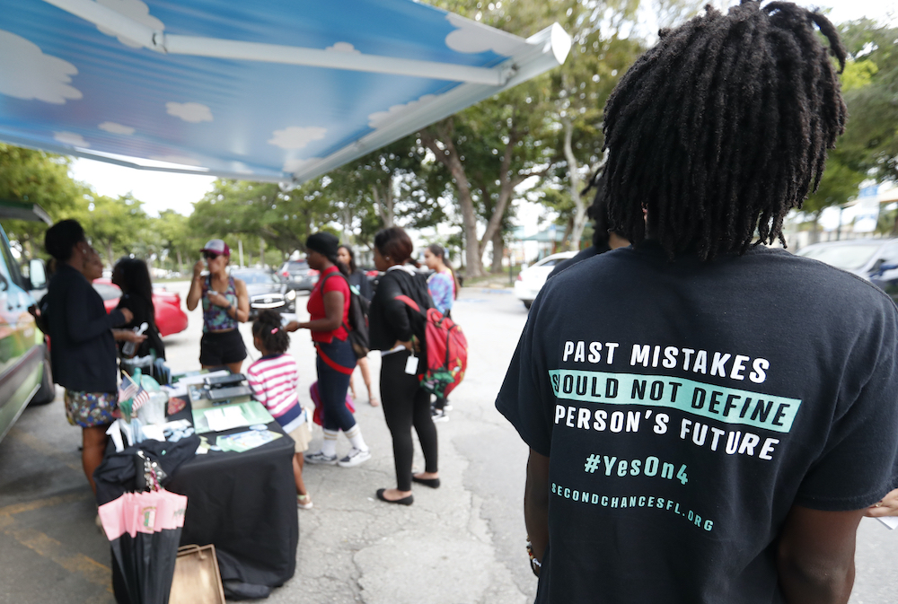 People gather around the Ben & Jerry's "Yes on 4" truck as they learn about Amendment 4, which in 2018 asked Florida voters to restore the voting rights of people with past felony convictions. Despite the amendment passing, as many as 700,000 former felons in the state are still blocked from voting due fees and fines