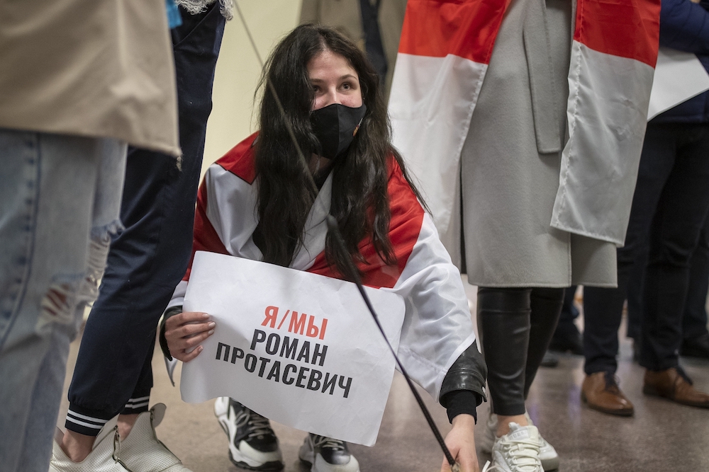 A woman holds a poster which reads "I'm/we're Raman Pratasevich" as she waits to see passengers of the Ryanair plane carrying Belarusian opposition journalist Raman Pratasevich at Vilnius International Airports in Vilnius, Lithuania, on Sunday, May 23, 2021.