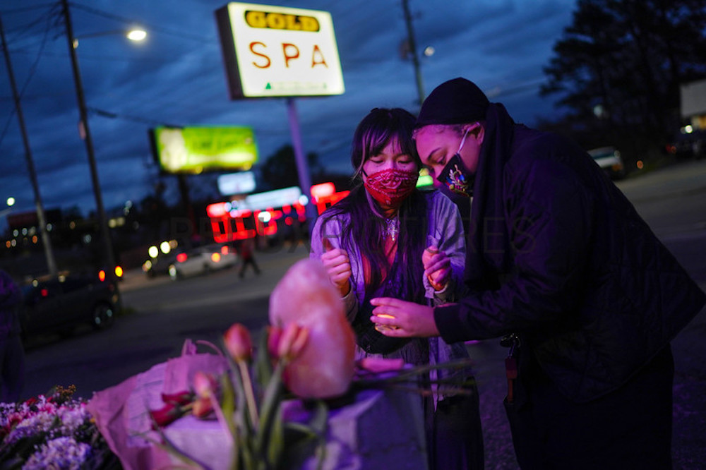 Two people light a candle at a makeshift memorial outside Gold Spa in Atlanta, March 18, 2021, where three women of Asian descent were killed.