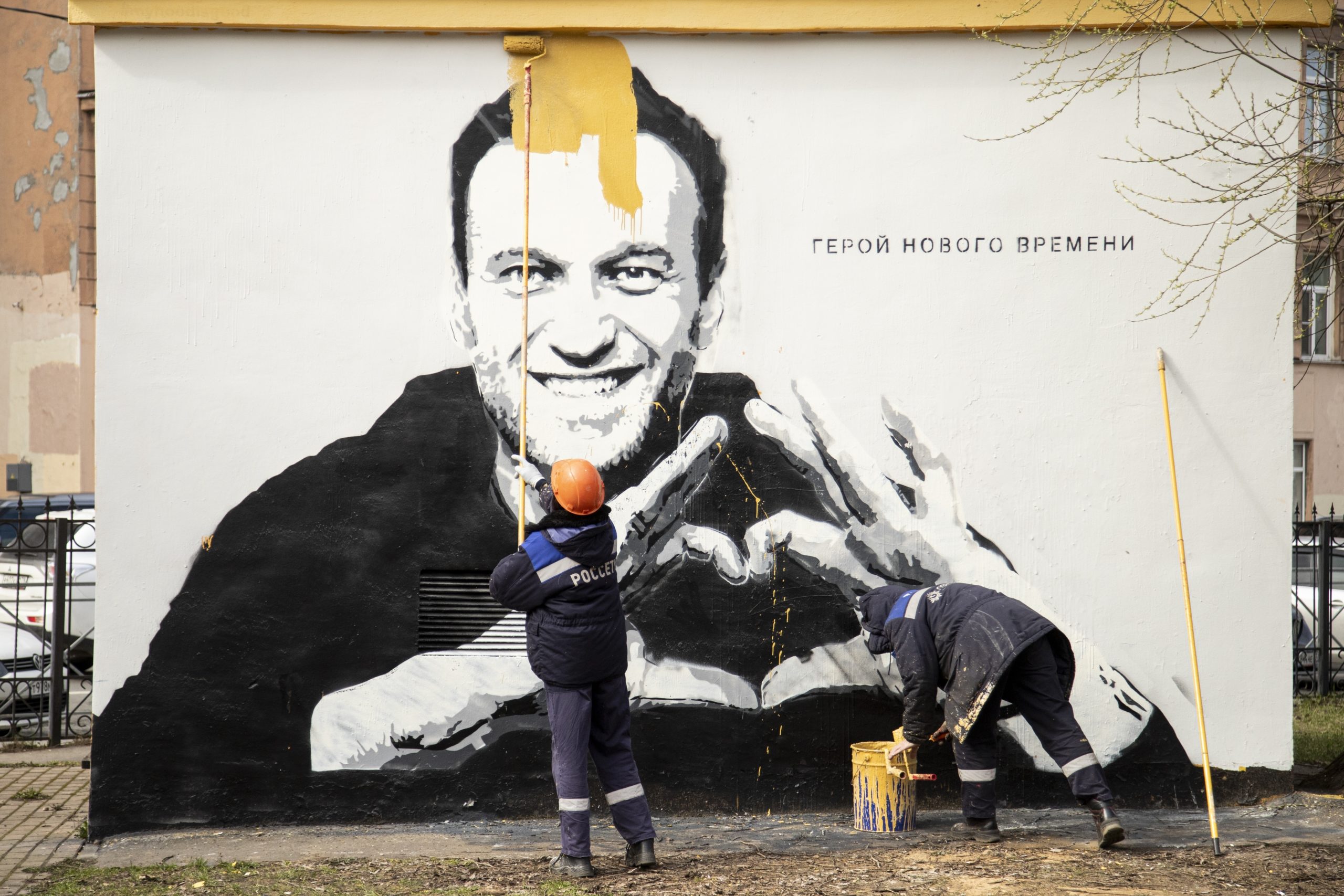 Municipal workers paint over graffiti of Russia's imprisoned opposition leader Alexei Navalny in St. Petersburg, Russia, on, April 28, 2021. The words on the wall read "Hero of our time"