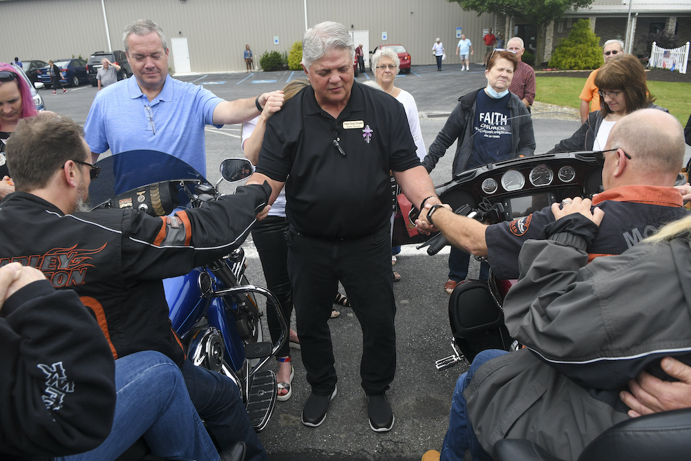 Pastor Doug Cresswell, center, holds the hands of bikers Greg Reser, of Shenandoah, Pa., left, and Jeff Gilfillan, of Schuylkill Haven, Pa., during the Blessing of the Bikers in the parking lot at Faith Church in Orwigsburg, Pa., on Sunday, June 13, 2021