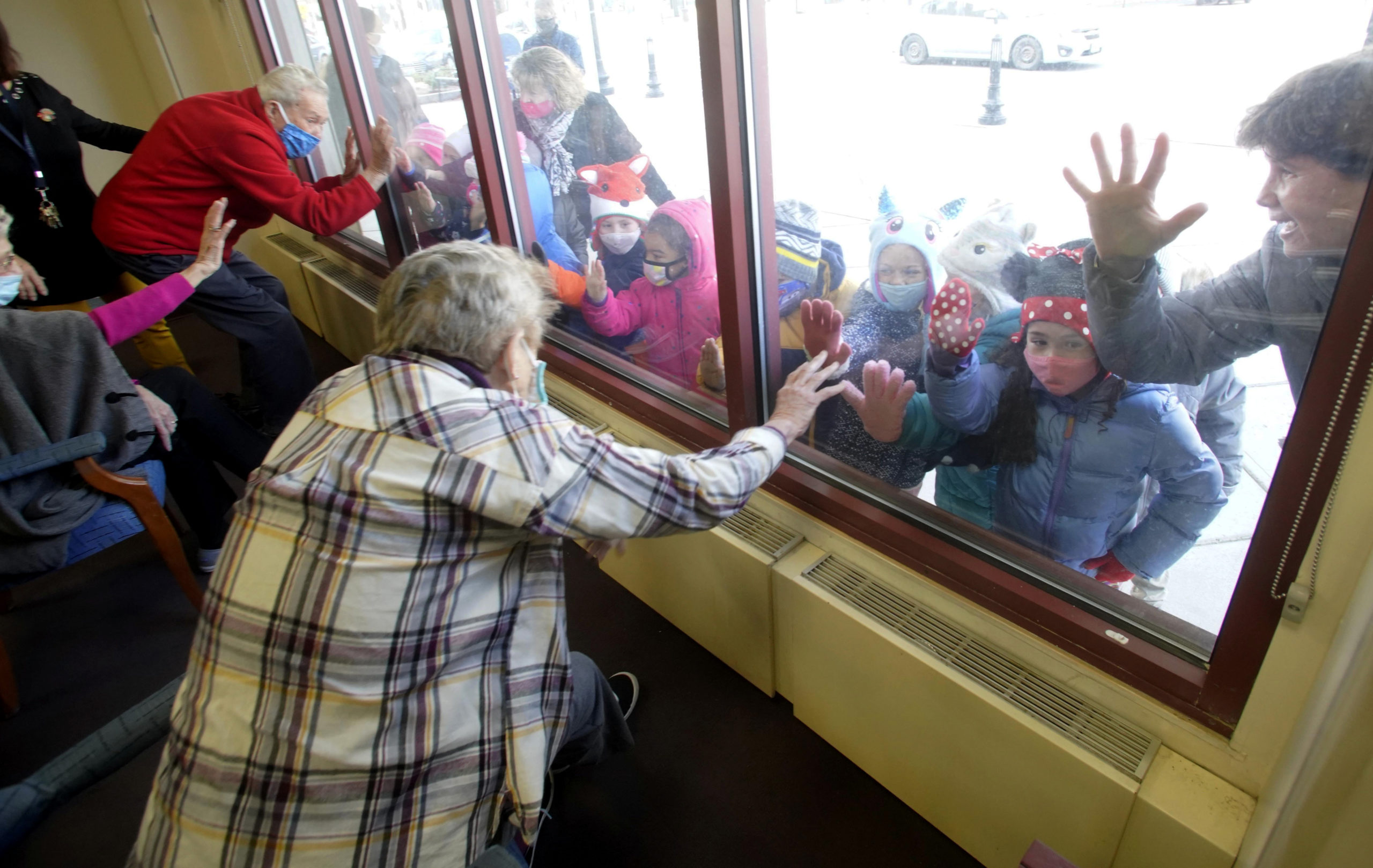 The pre-kindergarten group from the Boys and Girls Club visit through the window with members of the supportive daycare program at the Froio Senior Center in Pittsfield, Mass., in Nov. 2020 
