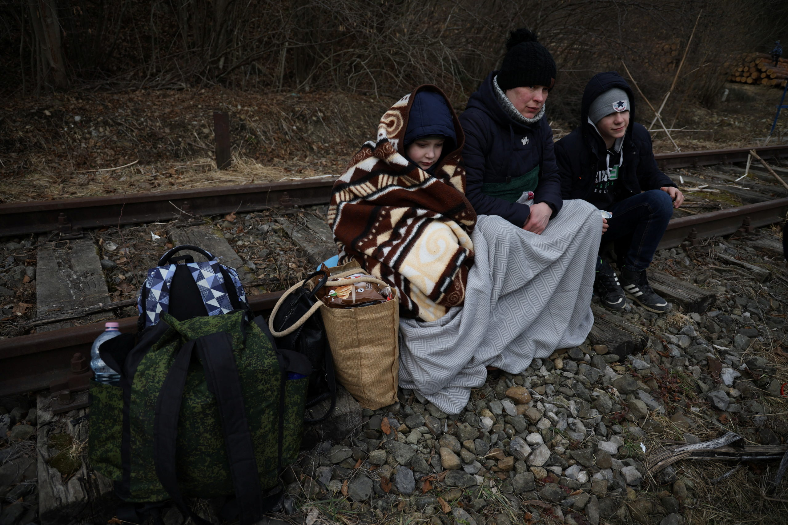 People sit on the railway after crossing the border between Poland and Ukraine, after Russia launched a massive military operation against Ukraine, in Kroscienko, Poland on Feb. 27, 2022 