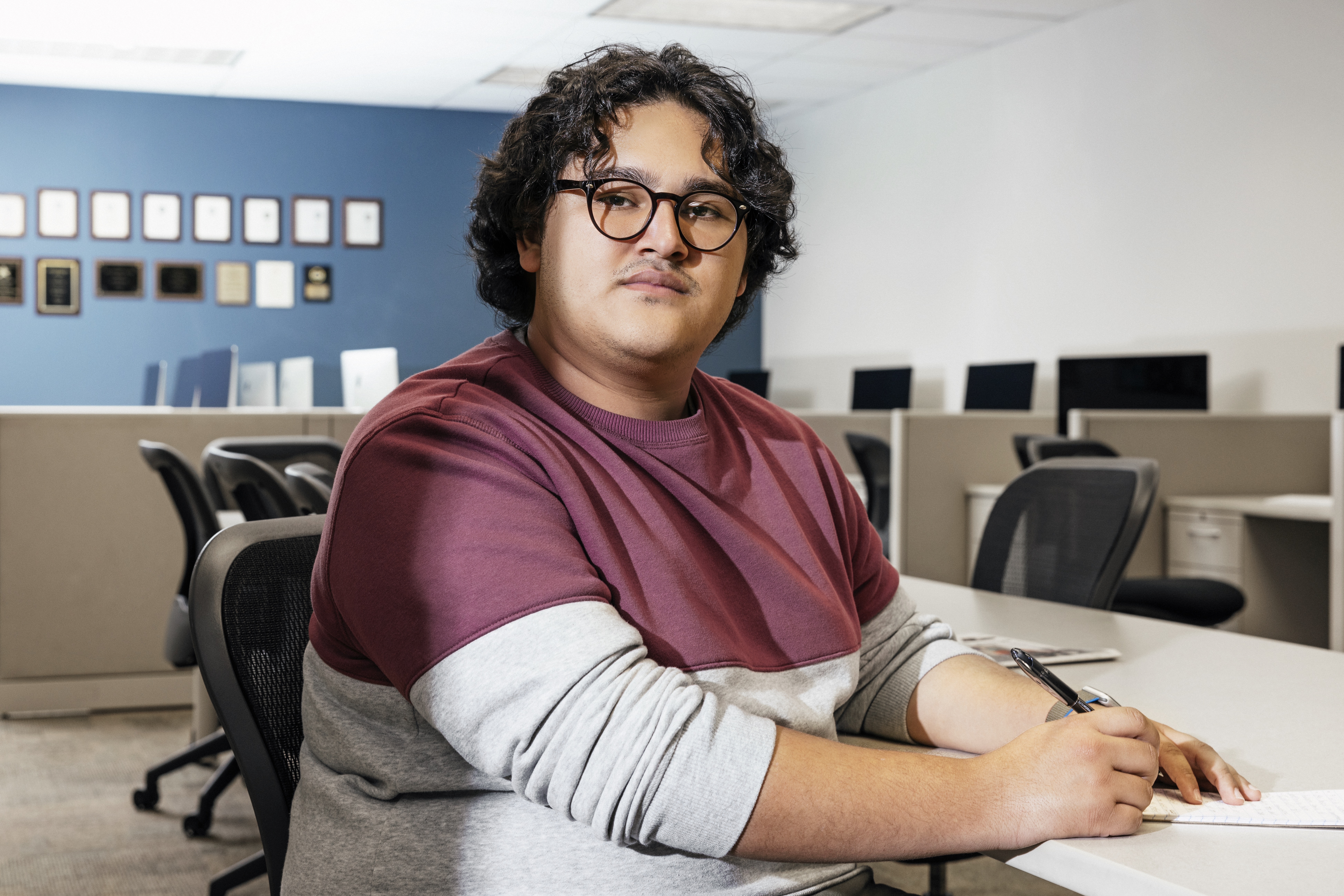 With a pen in hand, José Romero sits at his desk in the newsroom of Tarrant County College's student newspaper
