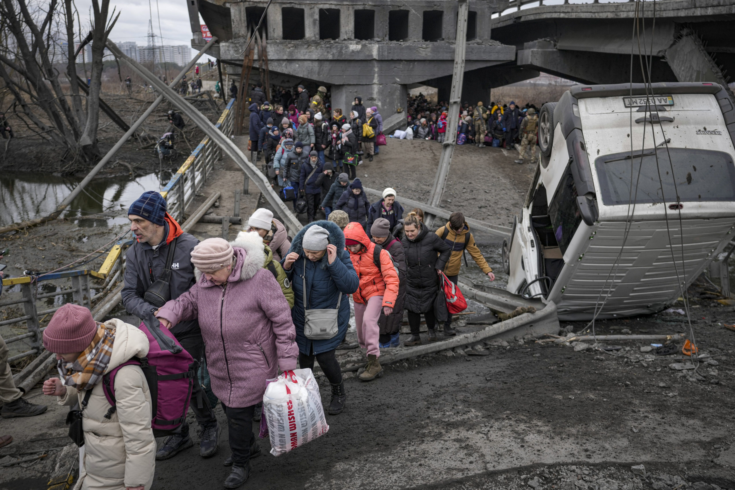 People cross the Irpin river on an improvised path under a bridge, that was destroyed by Ukrainian troops designed to slow any Russian military advance, while fleeing the town of Irpin, Ukraine, March 5, 2022