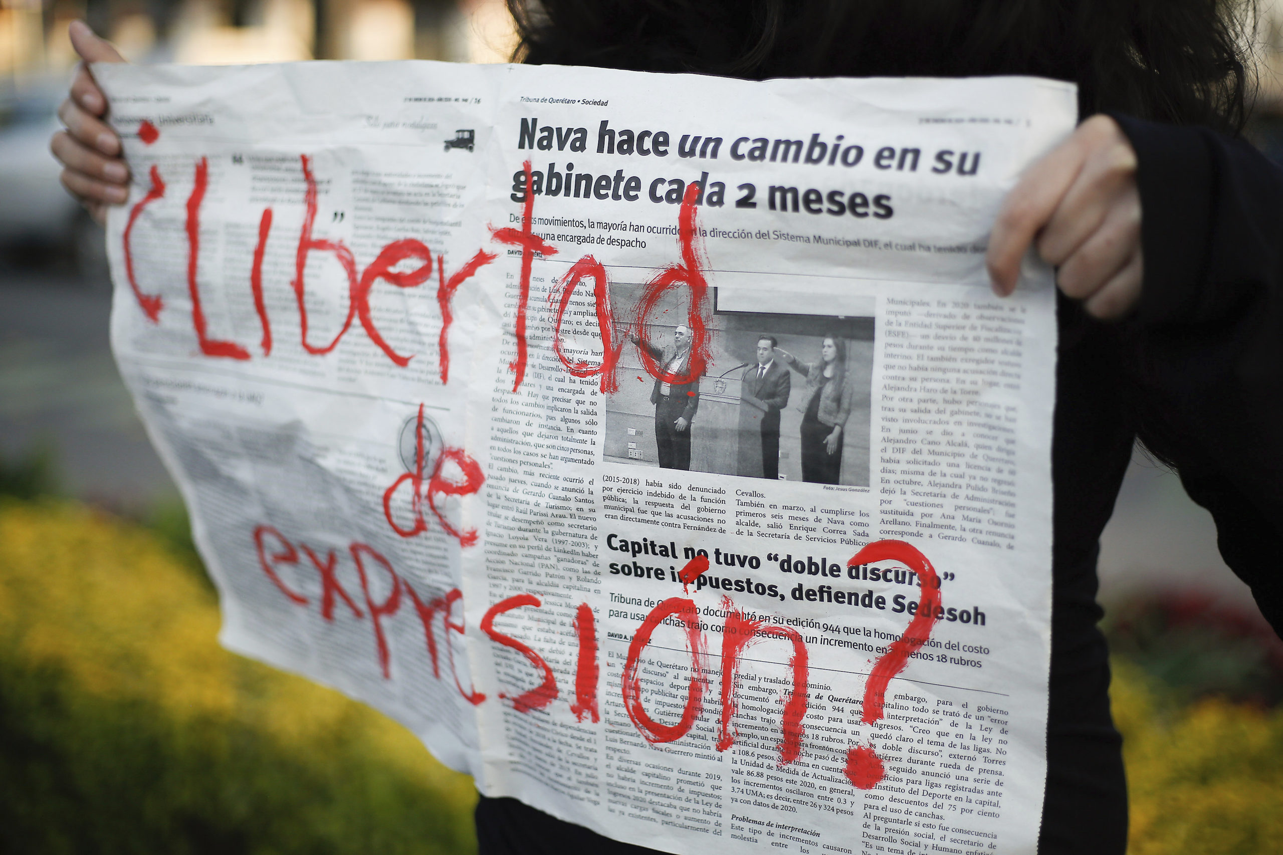 A protester holds up a newspaper spread that reads, in red paint, "¿Libertad de expresión?" (In English: Freedom of expression?)