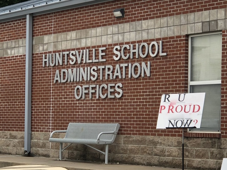A photo of the Huntsville, Arkansas, School Administration Building with a "R U Proud Now" sign in front