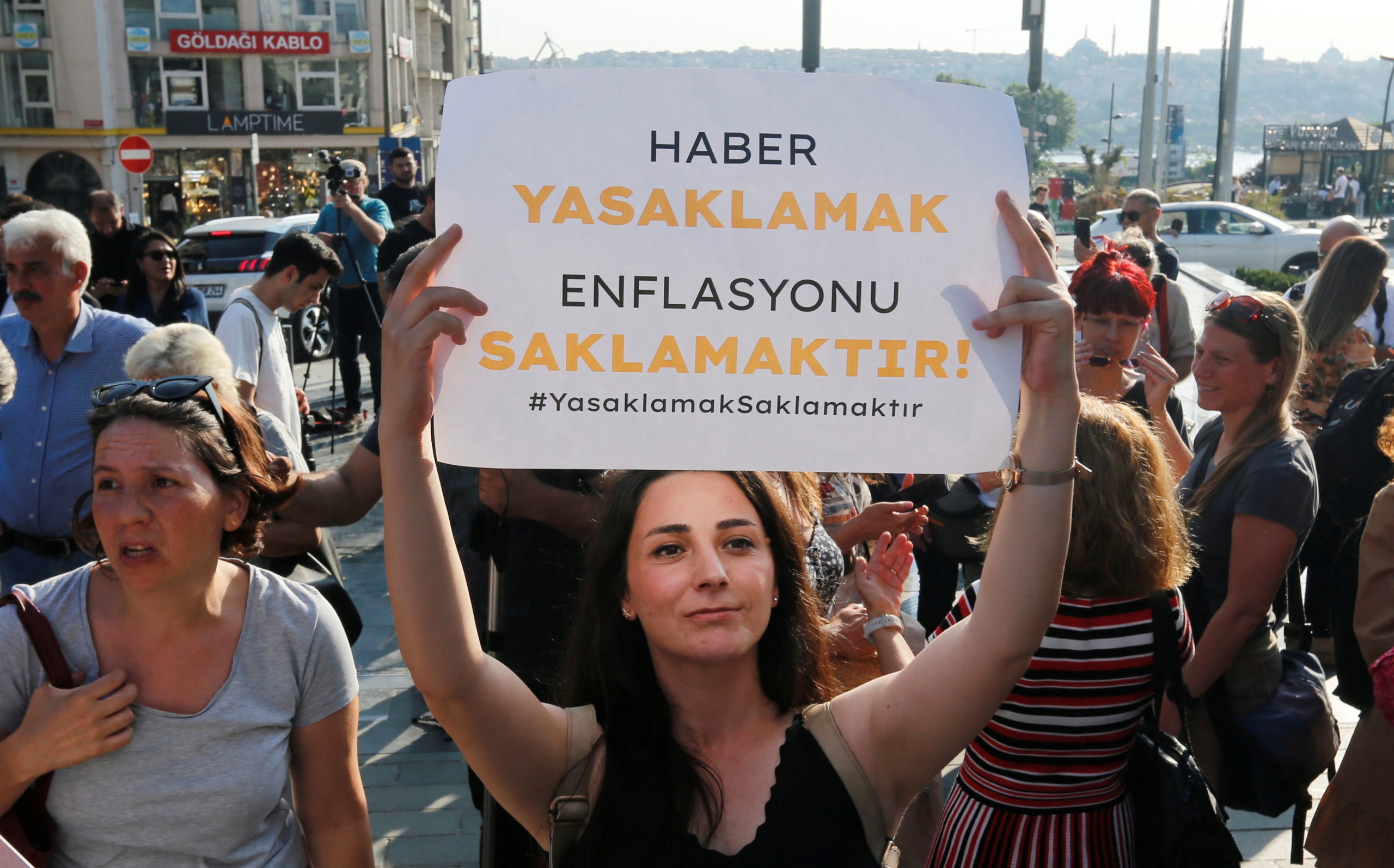 A woman holds a banner that reads, in Turkish: "Banner reads: "banning news means hiding inflation"