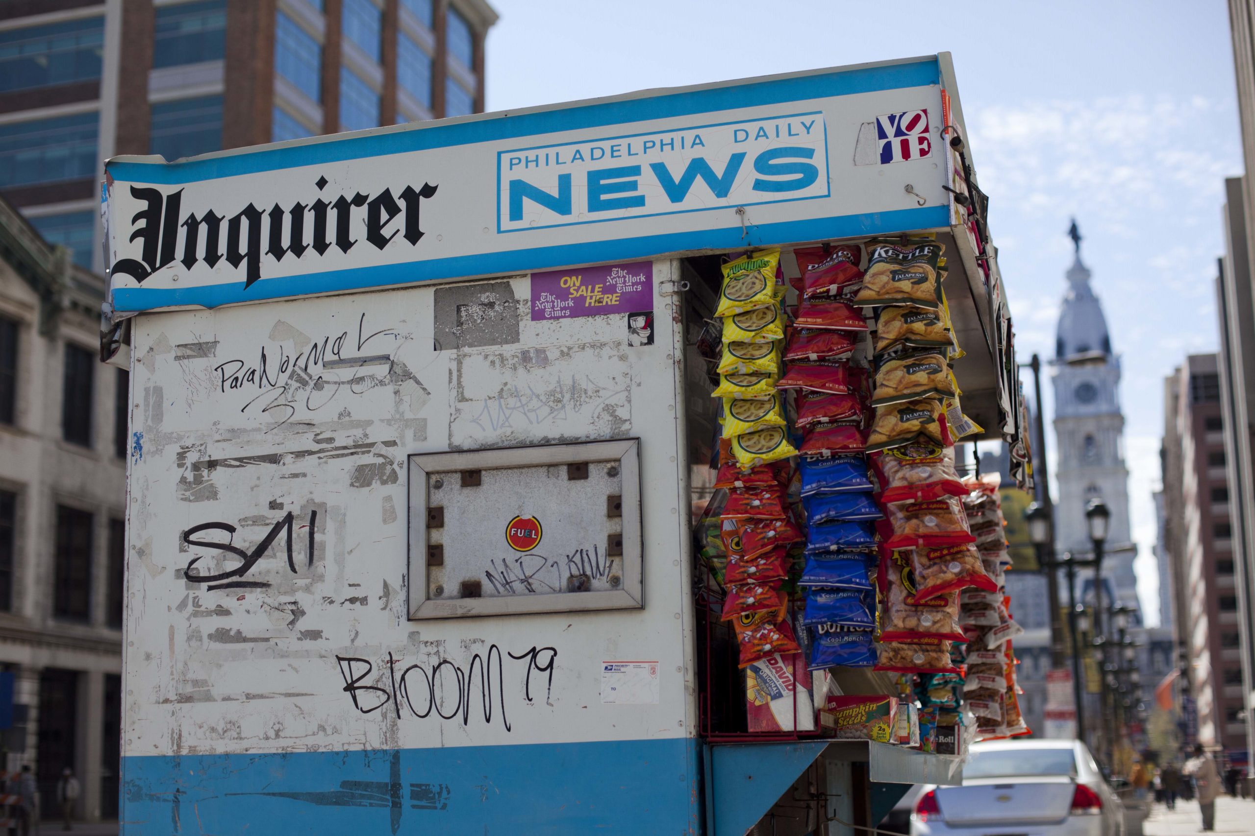 A newsstand displays the logos of The Philadelphia Inquirer outside of City Hall