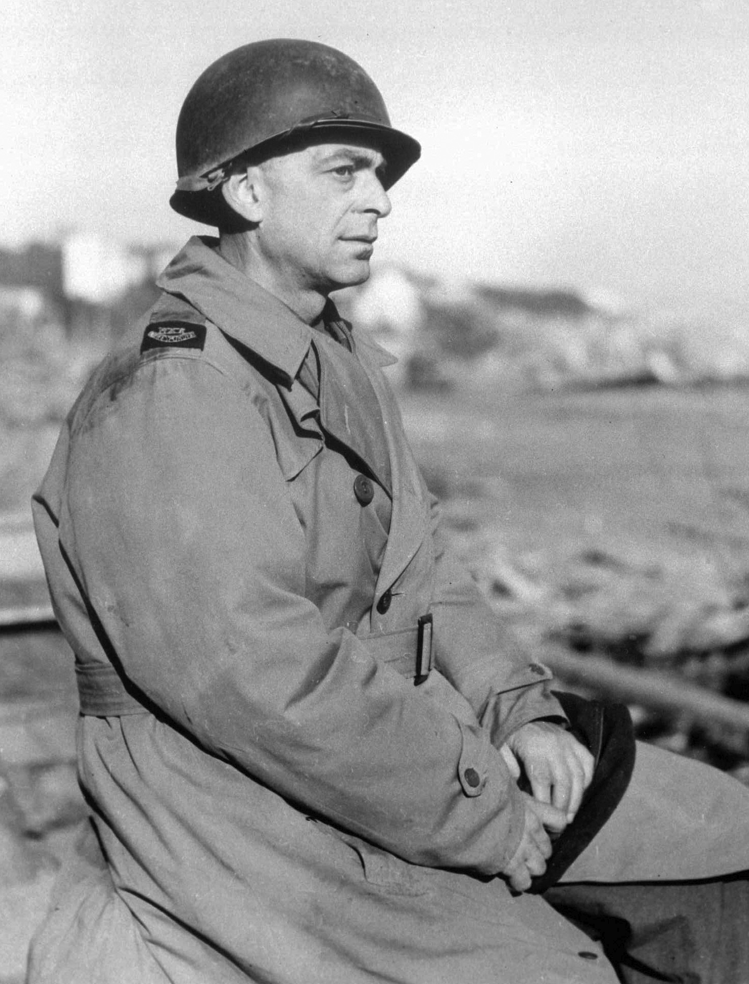 black and white picture of a man in world war two US military garb and a helmet, he is sitting so only his profile is visible from the side